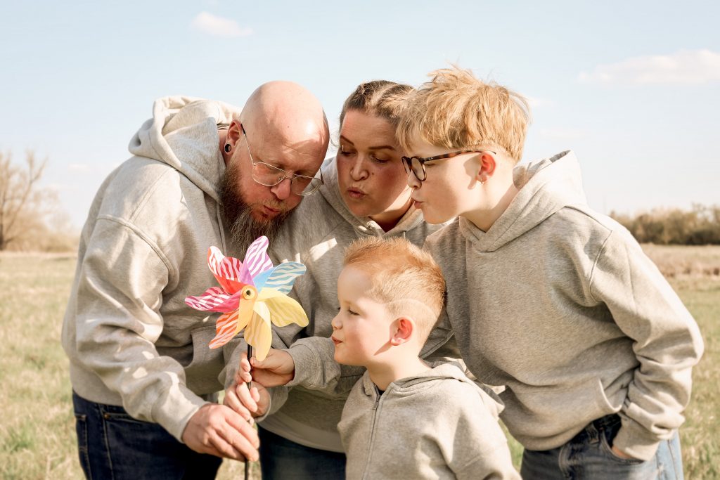 Familie pustet gemeinsam ein Windrad auf einer Wiese in Hochheim.