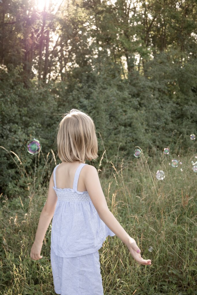 Mädchen schaut verträumt Seifenblasen bei einem Familien-Shooting auf einer Wiese bei Hochheim hinterher.